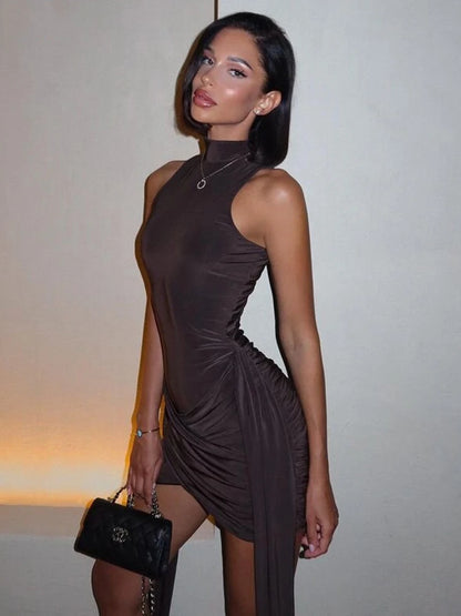 Brown bodycon mini dress with ruched detailing. Features slight stretch, tank sleeves, a turtleneck neckline, and an asymmetrical silhouette.