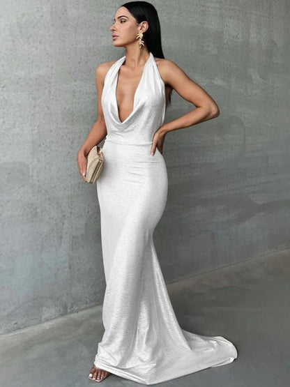 Woman wearing a sparkly white bodycon maxi dress with a mermaid silhouette, deep halter neck and backless design